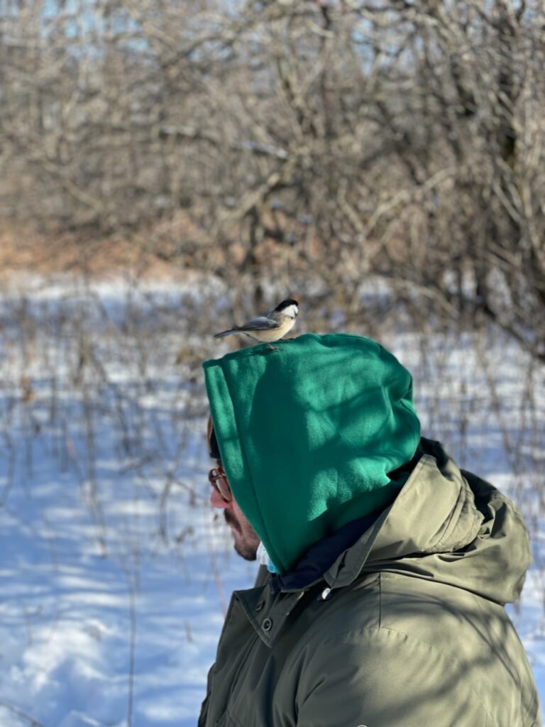 Image of author Jean-Christophe Rehel with bird on his head out in the bush.